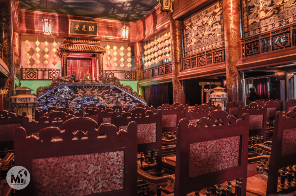 Interior del teatre, on es poden veure les cadires de fusta, tapissades de teles vermelles i daurades i l'escenari, amb un parell de gongs a cada banda